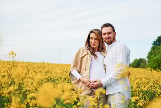 Pregnant couple by a field of yellow flowers photo