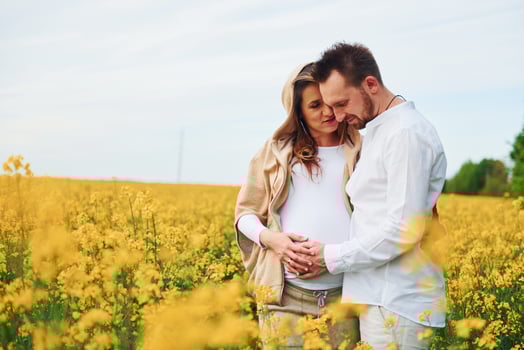 Pregnant couple by a field of yellow flowers photo