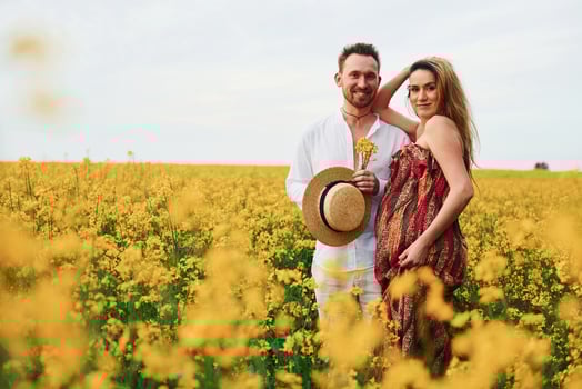 Pregnant couple by a field of yellow flowers photo