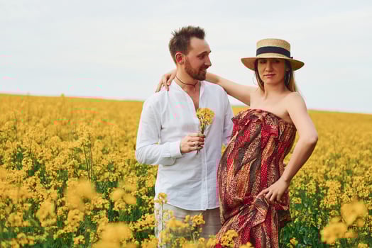 Pregnant couple by a field of yellow flowers photo
