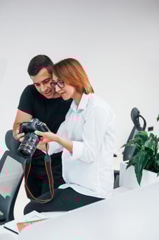 Man in black clothes watching photos on the female's photographer camera