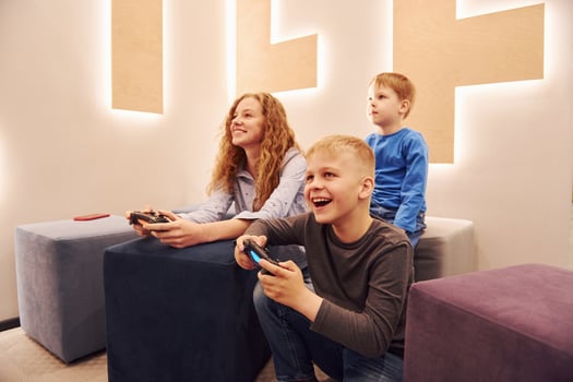 Cheerful kids sitting indoors and playing video games together photo