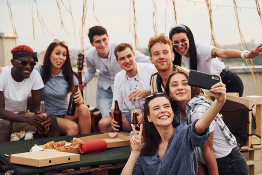 Girl making selfie. With delicious pizza. Group of young people in casual clothes have a party at rooftop together at daytime photo