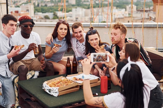 With delicious pizza. Group of young people in casual clothes have a party at rooftop together at daytime photo