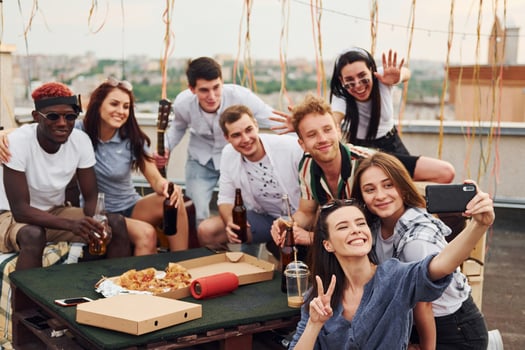 Girl making selfie. With delicious pizza. Group of young people in casual clothes have a party at rooftop together at daytime photo