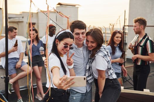 Taking selfie. Group of young people in casual clothes have a party at rooftop together at daytime photo