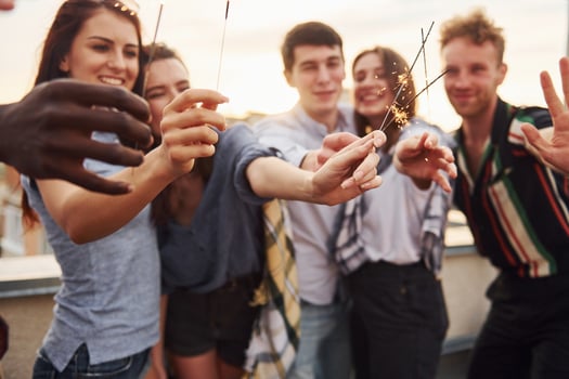 With sparklers in hands. Group of young people in casual clothes have a party at rooftop together at daytime photo