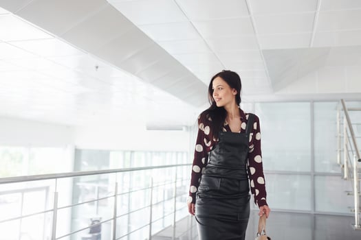 Beautiful young brunette in black skirt indoors in office or airport. Having free time photo