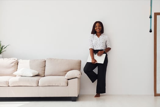 Young african american woman in formal clothes standing with laptop in hands indoors photo