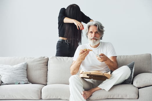 Wathing TV with scary woman with black hair near him. Senior stylish modern man with grey hair and beard indoors photo