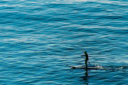A man rowing standing on a surf table on the deep blue sea photo