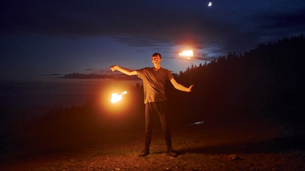 Photo with a long exposure. Fire show by man in dress in night Carphatian mountains. Beautiful landscape Pro Photo