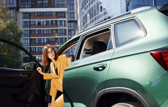 Walks out from automobile. Young fashionable woman in burgundy colored coat at daytime with her car photo