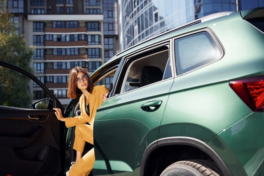 Walks out from automobile. Young fashionable woman in burgundy colored coat at daytime with her car photo