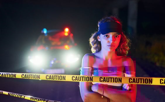 Cute young girl with curly hair and in hat standing outdoors near police line tape. Conception of crime or riot photo