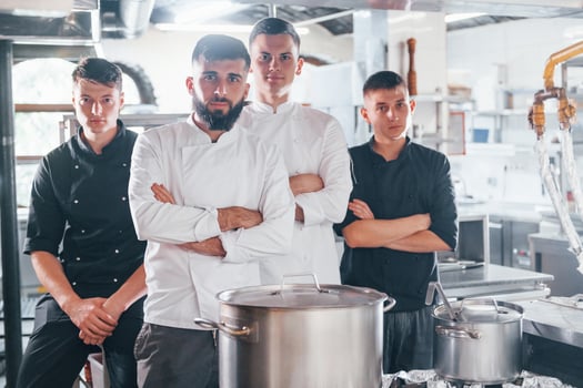 Group of people in white uniform standing together at kitchen. Cooking food photo