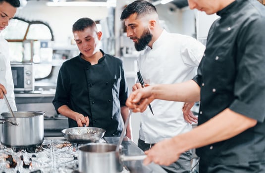 Group of people cooking food at kitchen together. Busy day at work photo