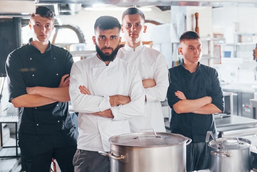 Group of people in white uniform standing together at kitchen. Cooking food photo