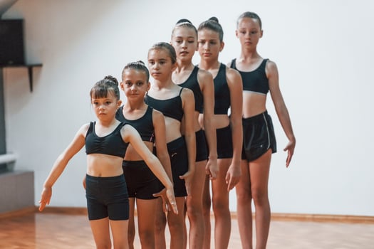 Daily routine. Group of female kids practicing athletic exercises together indoors photo