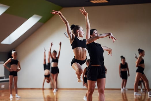 Woman teaching and helping. Group of female kids practicing athletic exercises together indoors photo