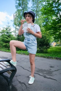 a teenage girl on a walk on a summer day in the park has lunch with noodles wok photo