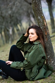 Image of young beautiful woman wearing rain jacket in cold weather. Thinker european girl in spring nature. photo