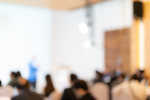 Blurry seminar hall with audience student in it. This room are arranged by round circle group table that appropriate for workshop. photo