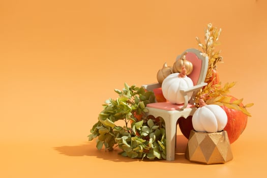 Creative autumn still life composition. Gold and white decorative pumpkins with chair and dry flowers photo
