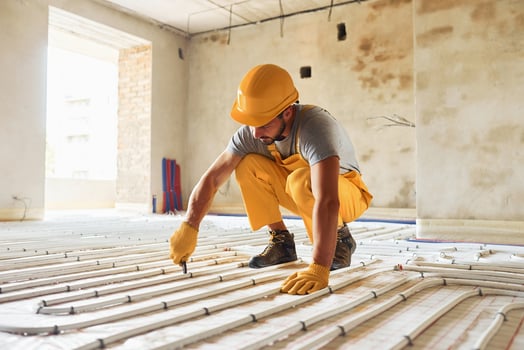 Worker in yellow colored uniform installing underfloor heating system photo