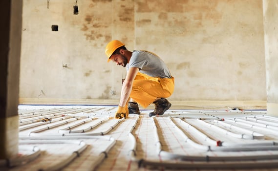 Worker in yellow colored uniform installing underfloor heating system photo