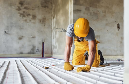 Worker in yellow colored uniform installing underfloor heating system photo