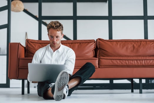 Having a rest. Caucasian young guy in elegant white shirt indoors at home photo
