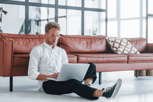 Having a rest. Caucasian young guy in elegant white shirt indoors at home photo