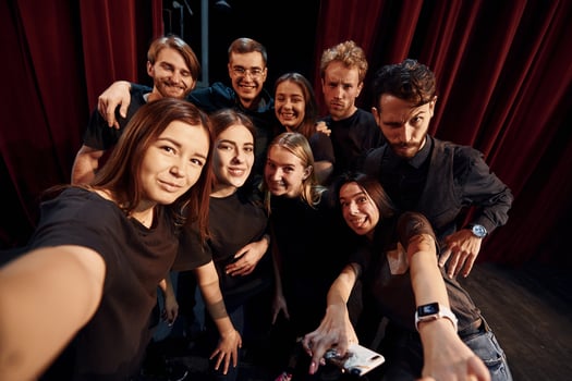 Making selfie. Group of actors in dark colored clothes on rehearsal in the theater photo