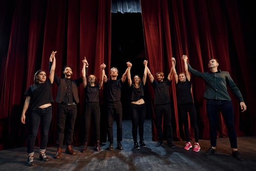 People bowing to audience. Group of actors in dark colored clothes on rehearsal in the theater photo