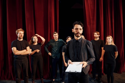 Expressionalible guy practicing his role. Group of actors in dark colored clothes on rehearsal in the theater photo