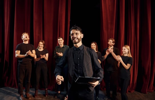 Man is practicing his role. Group of actors in dark colored clothes on rehearsal in the theater photo