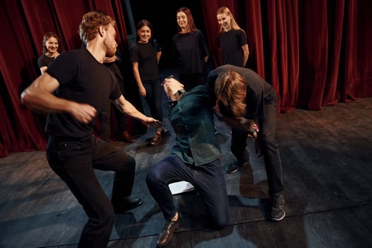 Fight scene. Group of actors in dark colored clothes on rehearsal in the theater photo