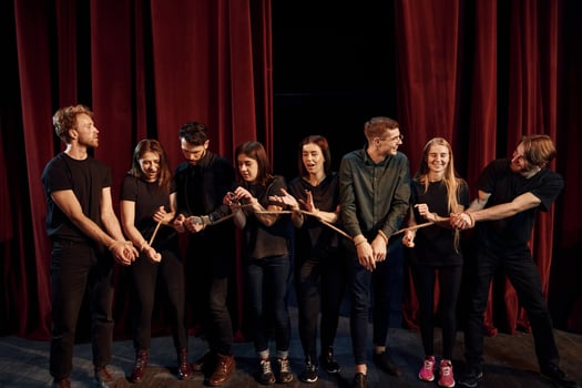 With rope in hands. Group of actors in dark colored clothes on rehearsal in the theater photo