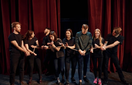 With rope in hands. Group of actors in dark colored clothes on rehearsal in the theater photo