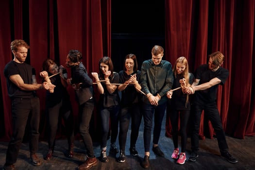 With rope in hands. Group of actors in dark colored clothes on rehearsal in the theater photo