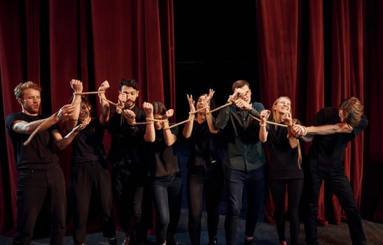 Knot in the hands. Group of actors in dark colored clothes on rehearsal in the theater photo