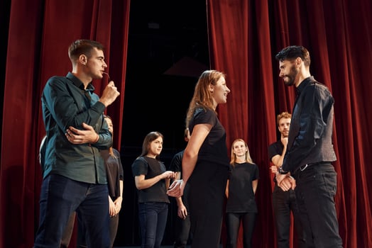Two people talking. Group of actors in dark colored clothes on rehearsal in the theater photo