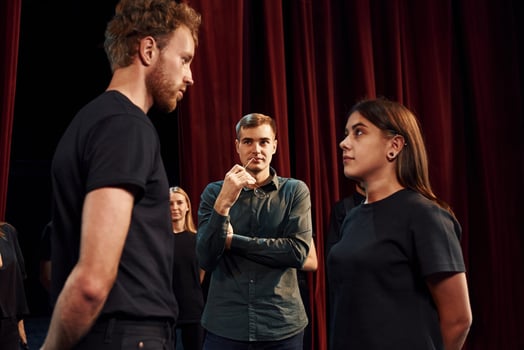 Two people talking. Group of actors in dark colored clothes on rehearsal in the theater photo