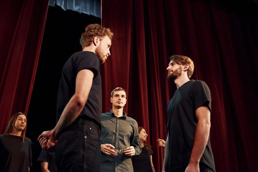 Two people talking. Group of actors in dark colored clothes on rehearsal in the theater photo