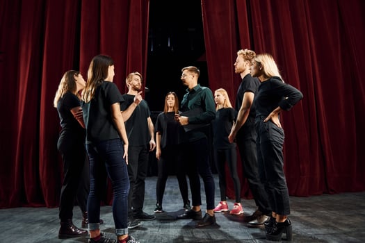Group of actors in dark colored clothes on rehearsal in the theater photo