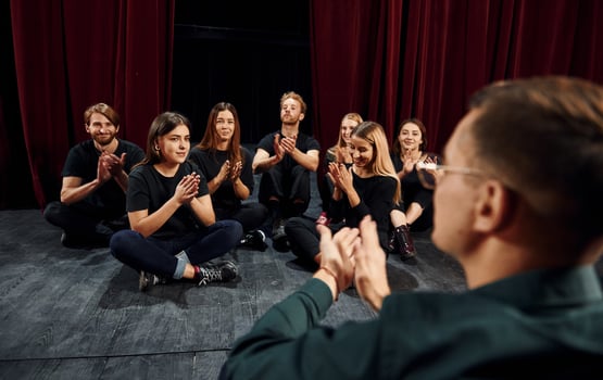 Sitting on the floor. Group of actors in dark colored clothes on rehearsal in the theater photo