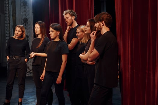 Side view. Group of actors in dark colored clothes on rehearsal in the theater photo