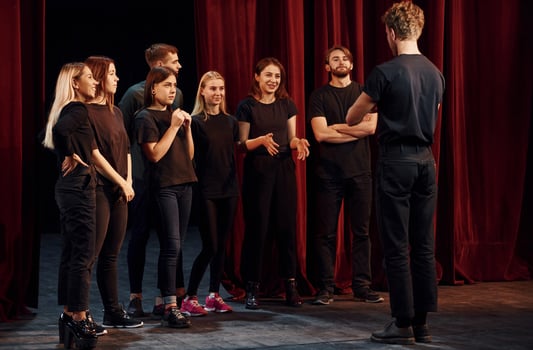 Group of actors in dark colored clothes on rehearsal in the theater photo