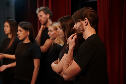 Side view. Group of actors in dark colored clothes on rehearsal in the theater photo